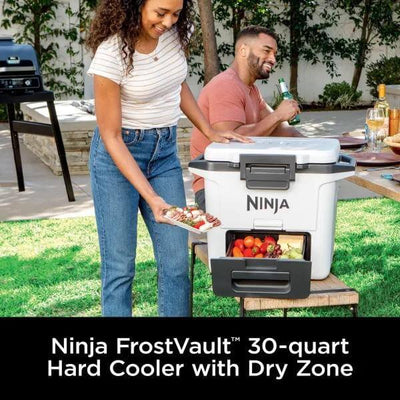 Two people with a Ninja FrostVault 30-quart hard cooler outdoors.