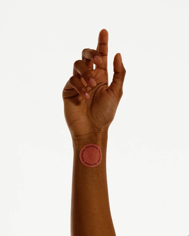 Hand with a red circular sticker on wrist against a white background
